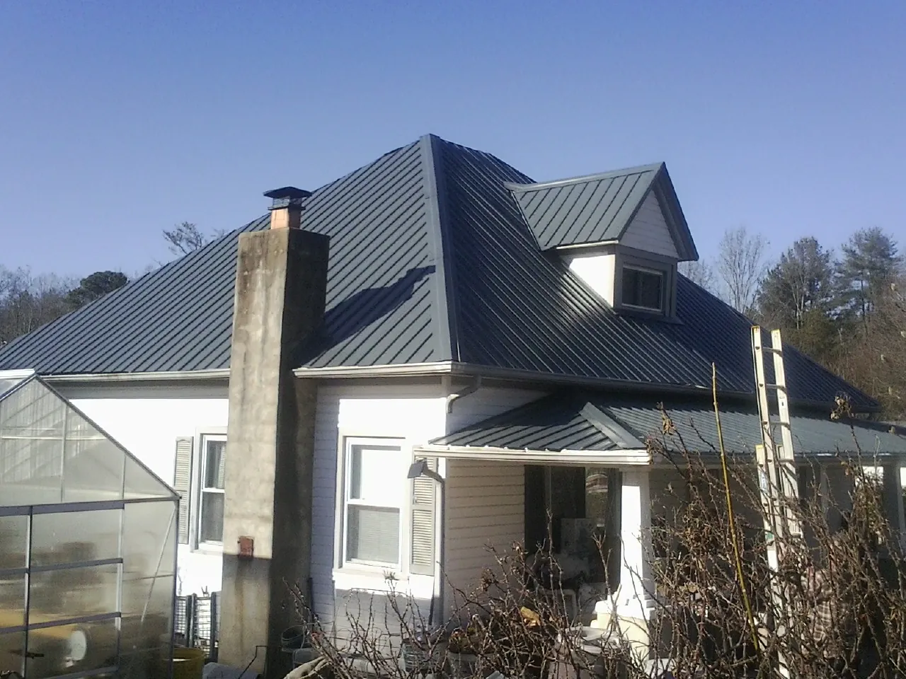 Dark blue standing seam metal roof on a white farmhouse with dormer — Slate & Tile Roof Repair by Roofing Brothers in Mishawaka
