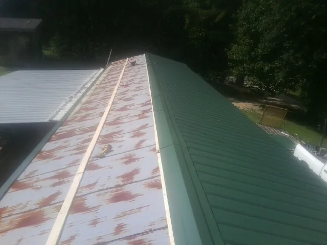 Old rusted panels beside newly installed green metal roofing — Wind Damage Roof Repair by Roofing Brothers in Mishawaka
