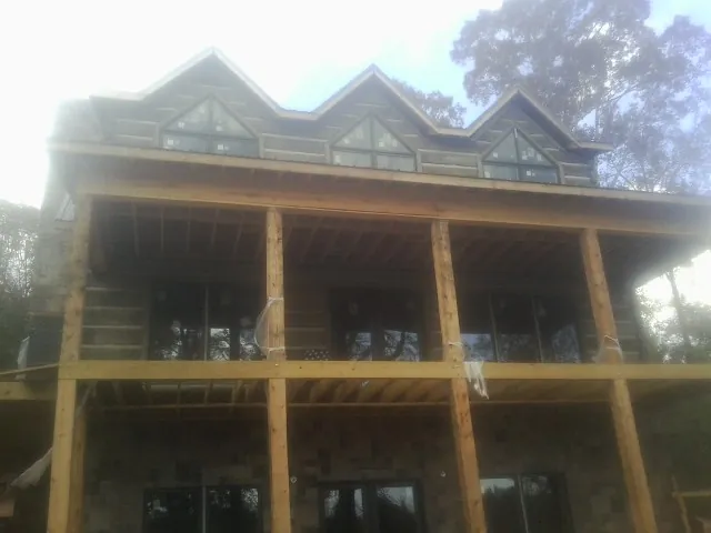 Dormers and porch framing on a large log home under construction — Roof Coating work by our crew in Mishawaka