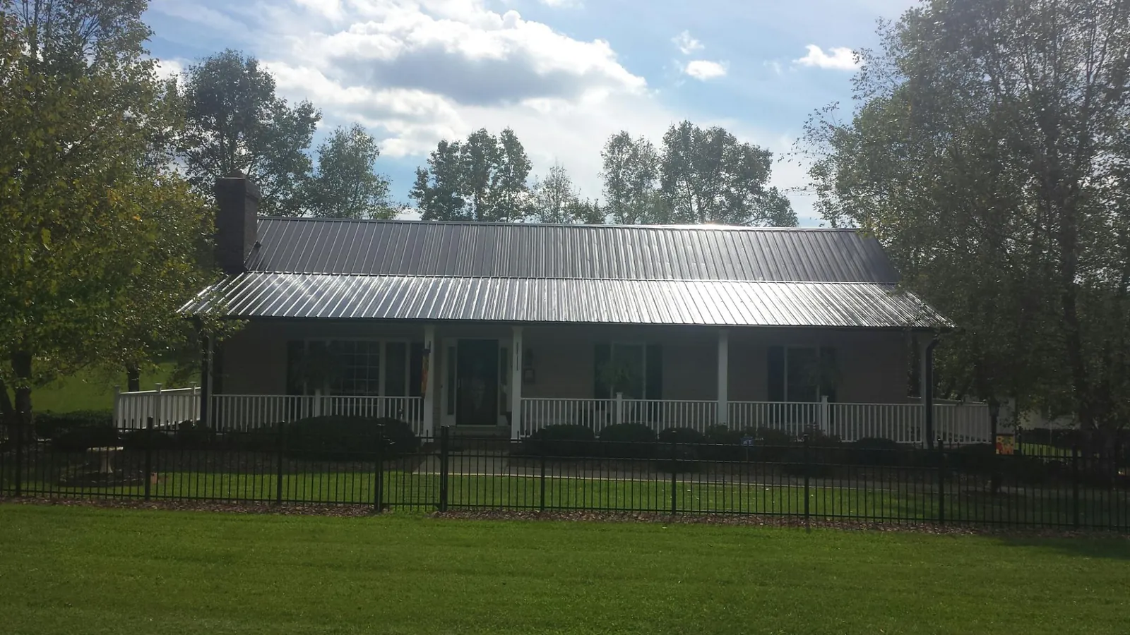 Gray metal roof on a brick ranch with a full width front porch — Gutter Guard Installation work by our crew in Mishawaka