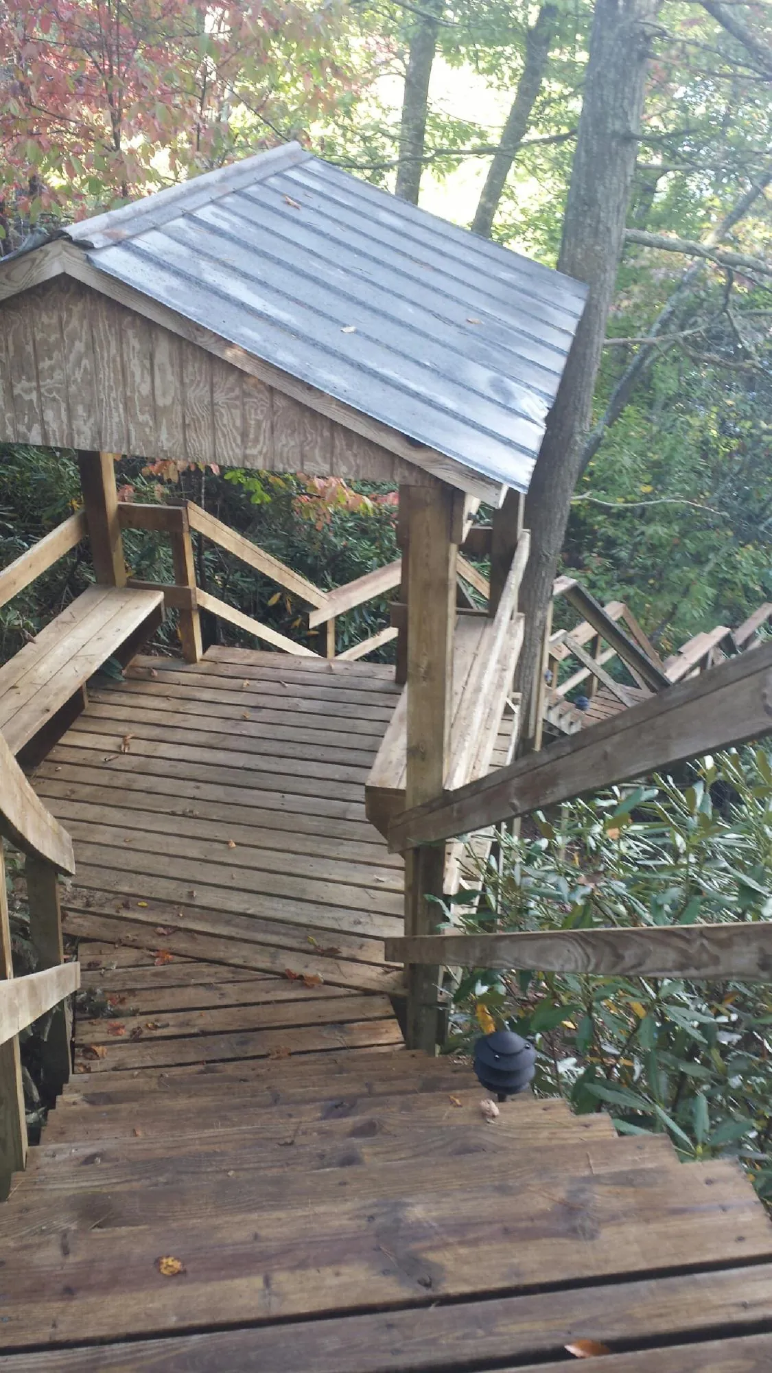 Metal roofed shelter over wooden steps on a wooded walkway — Skylight Repair & Installation work by our crew in Mishawaka